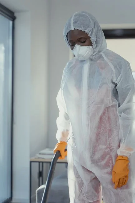 services-04 Homme anonyme portant des gants en latex jaunes et un t-shirt foncé, essuyant un miroir dans une salle de bain avec une serviette en papier
